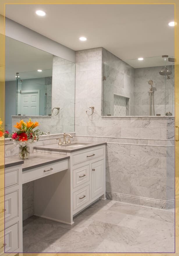 Modern bathroom vanity with marble finishes, large mirror, and vase of orange flowers
