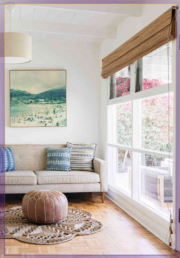 Bright sitting room with a gray chaise lounge, white rug, and large windows overlooking autumn trees.