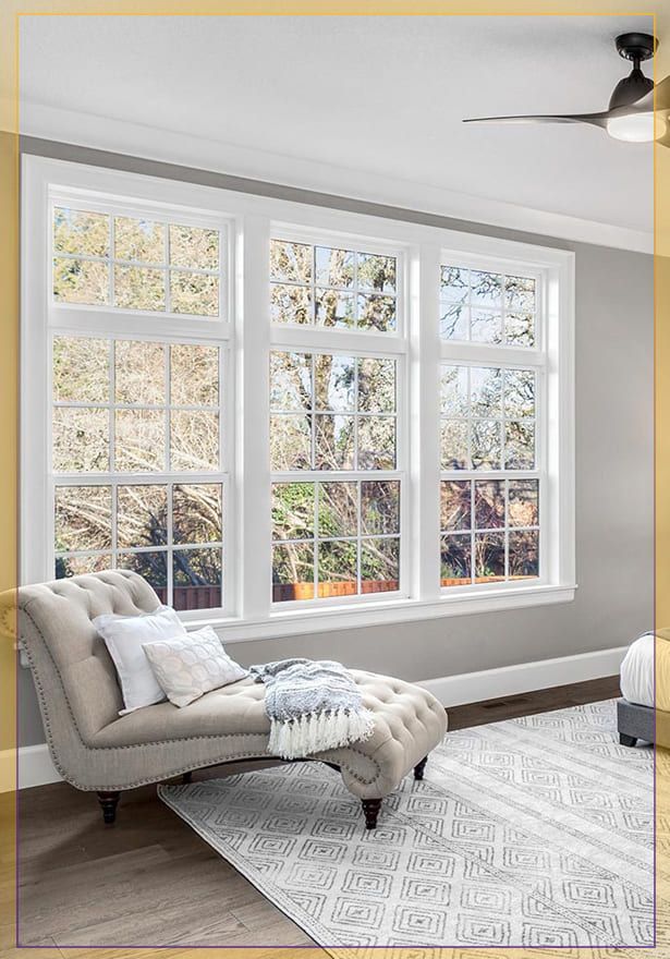 Bright living room with large windows, gray chaise lounge, patterned rug, and ceiling fan
