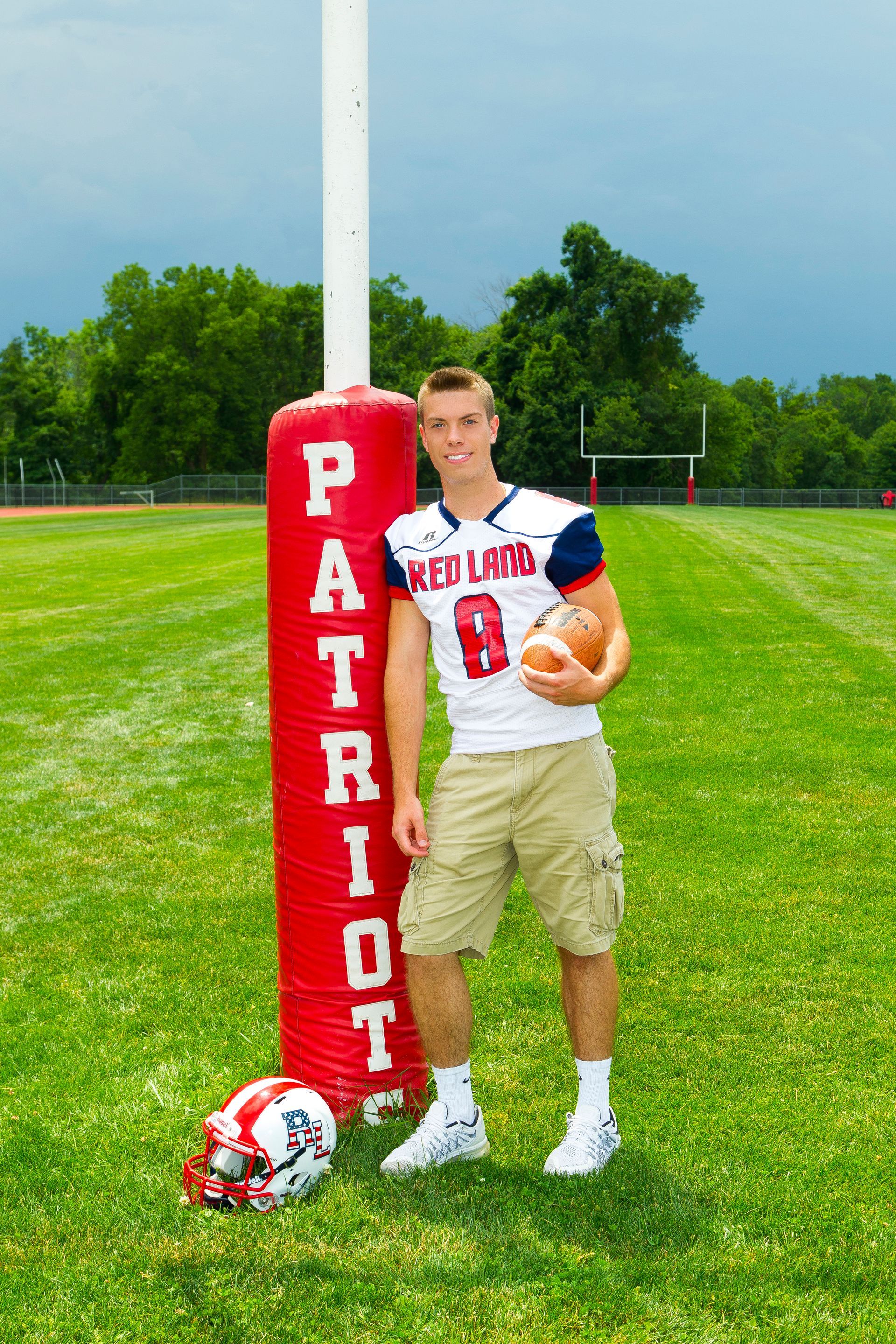 Football player in New Haven uniform standing by a red Patriots goalpost pad on a grassy field