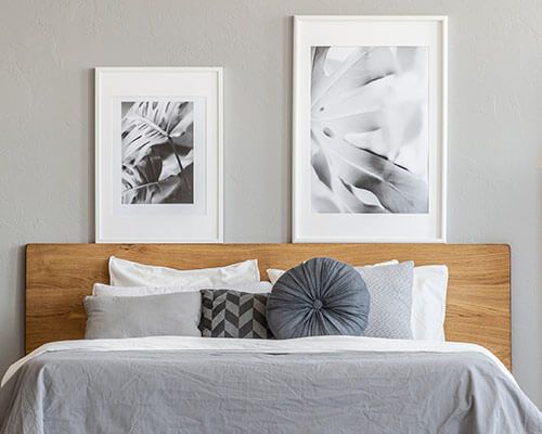 Modern bedroom with a wooden bed, gray bedding, and two framed black-and-white prints above the headboard