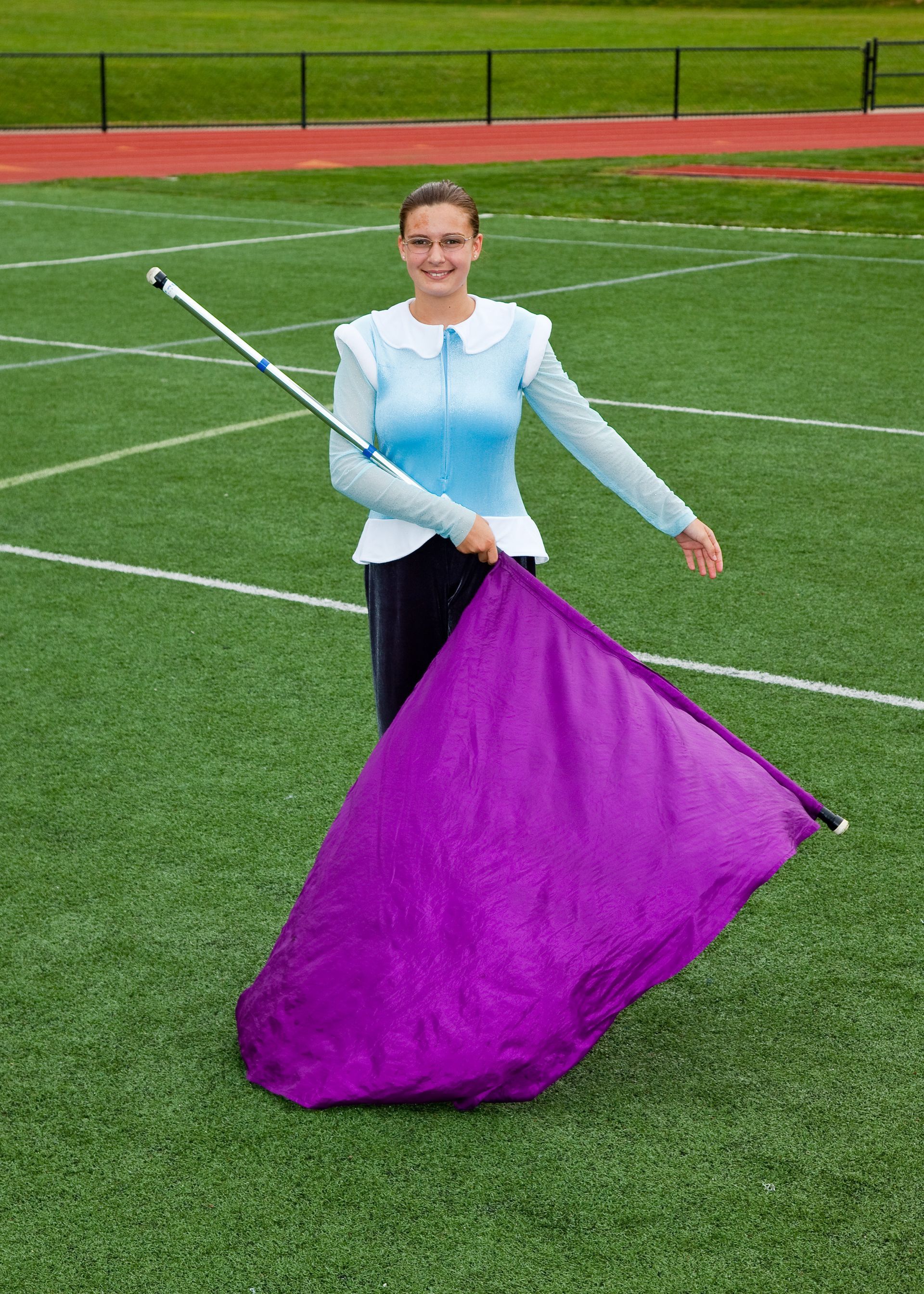 Person on a football field holding a purple flag with a white pole