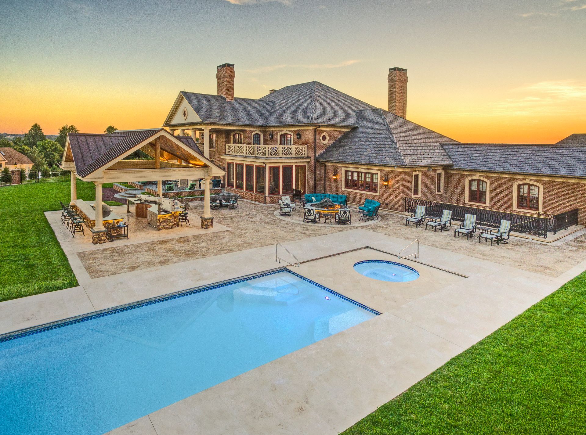 Luxury house with a large backyard pool, patio seating, and sunset sky