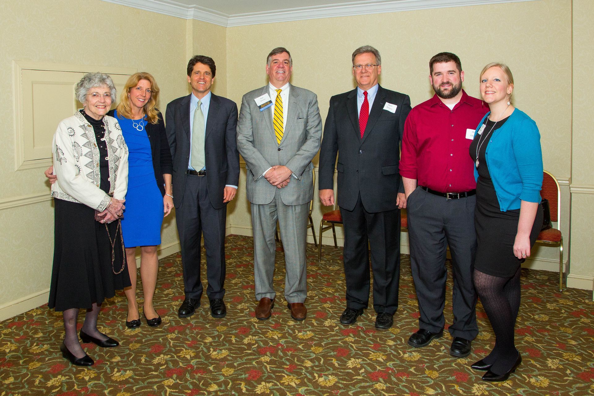 Seven people standing in a room, posing for a group photo.