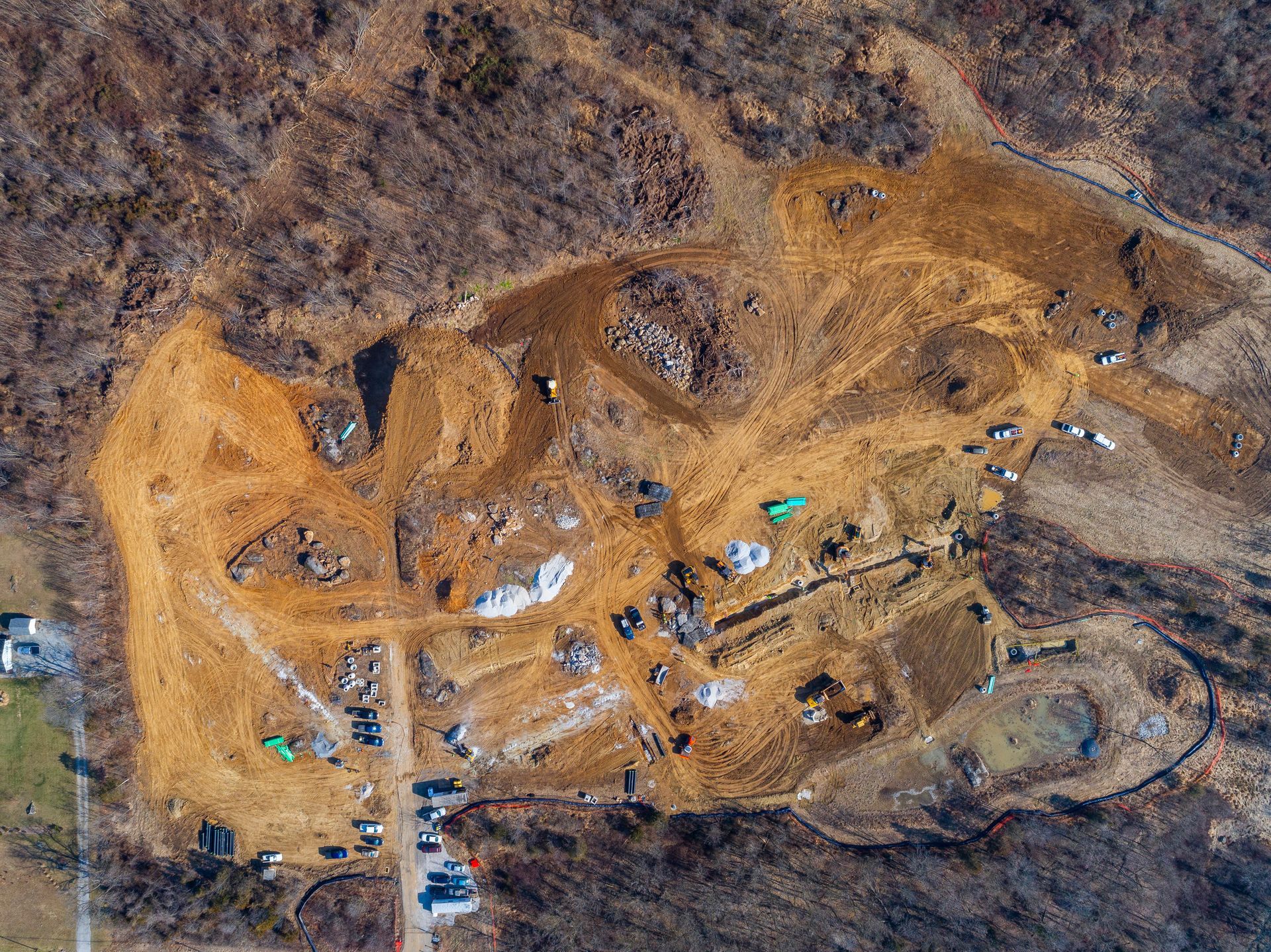 Aerial view of a large dirt construction site with machinery, vehicles, and winding excavation paths