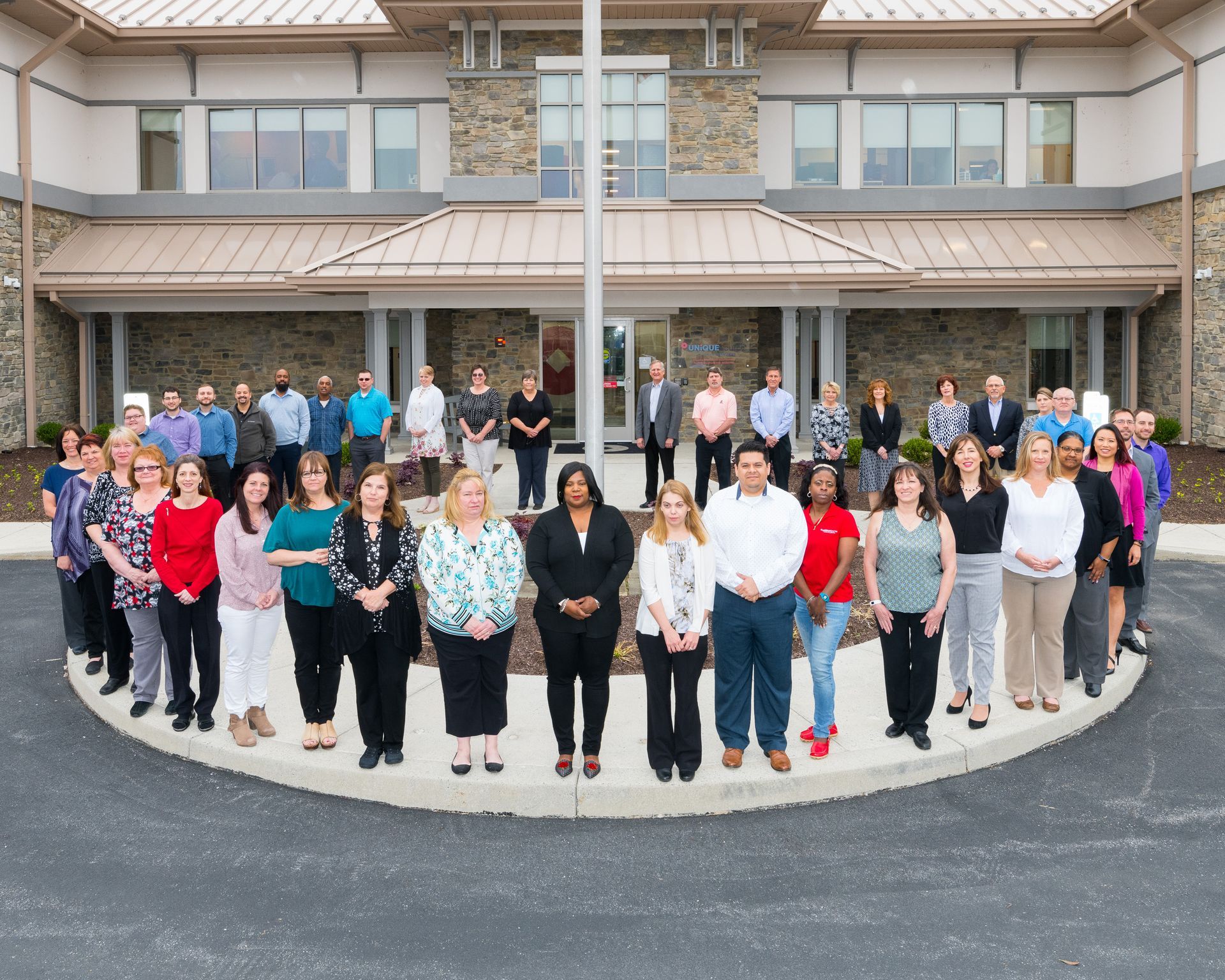 Large group standing in front of a building entrance, posing for a group photo