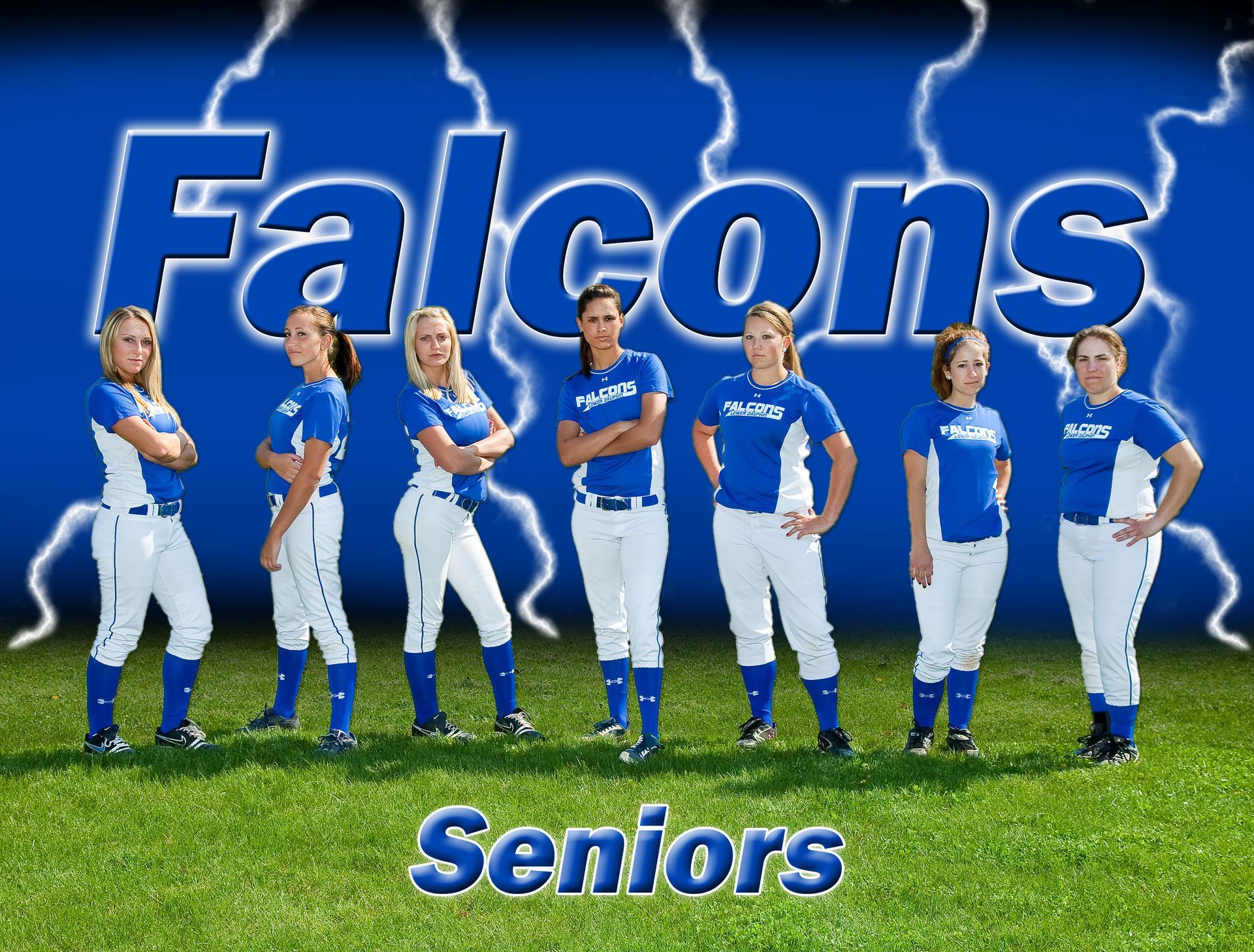 Falcons Seniors softball team in blue uniforms standing on grass before a large Falcons sign