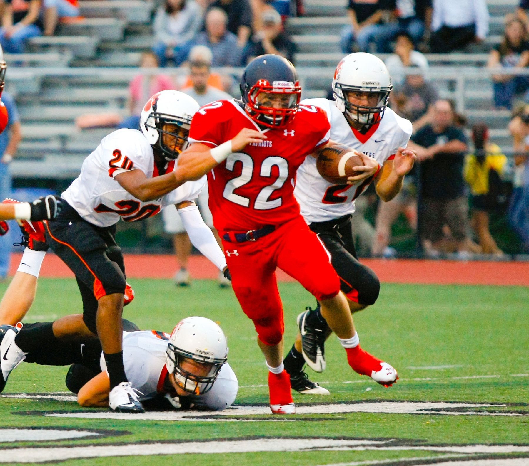 Football player in red jersey runs through tackles on the field during a game