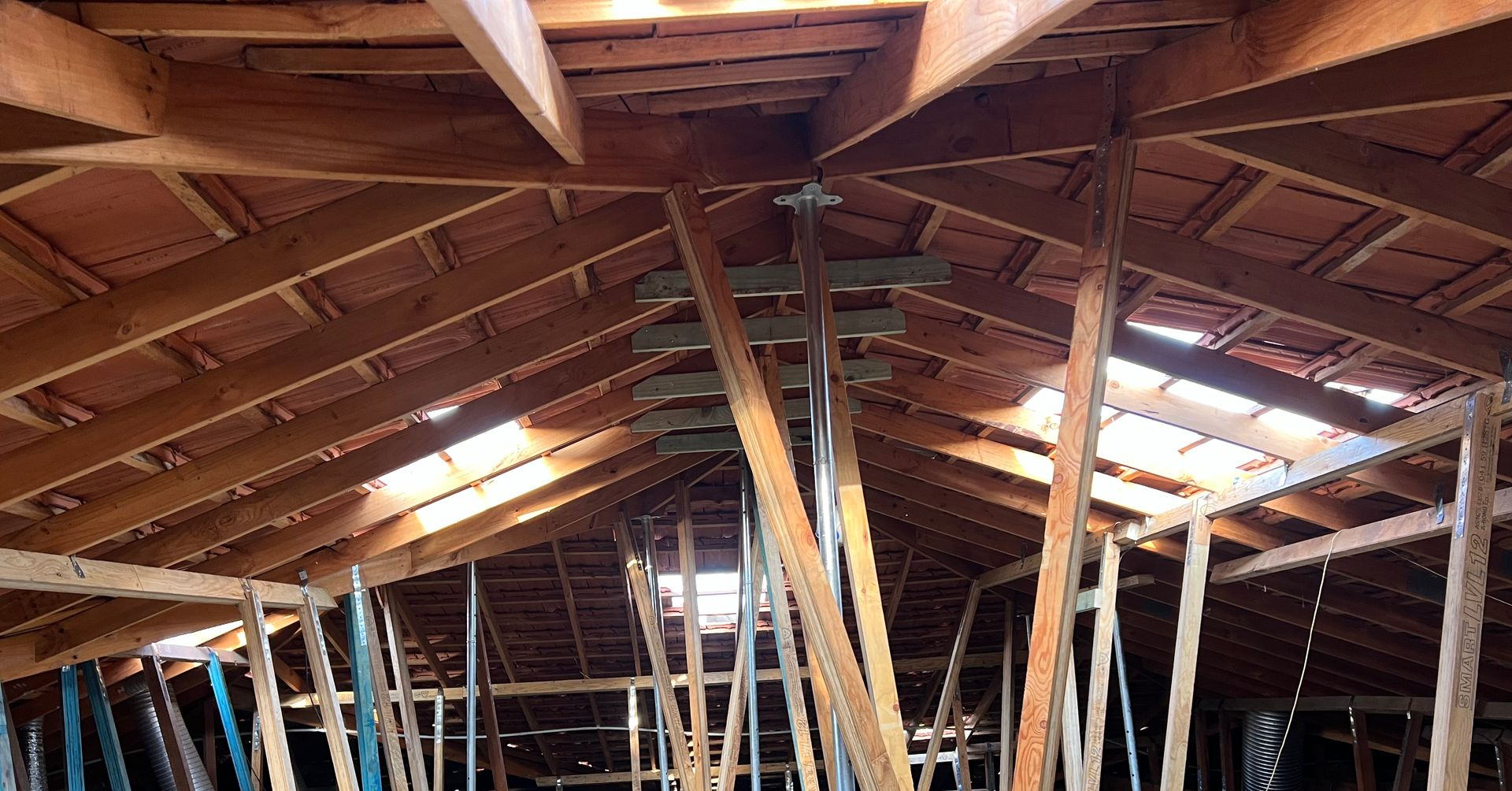 A low-angle view of a natural light-colored wooden roof structure featuring exposed beams and trusses.