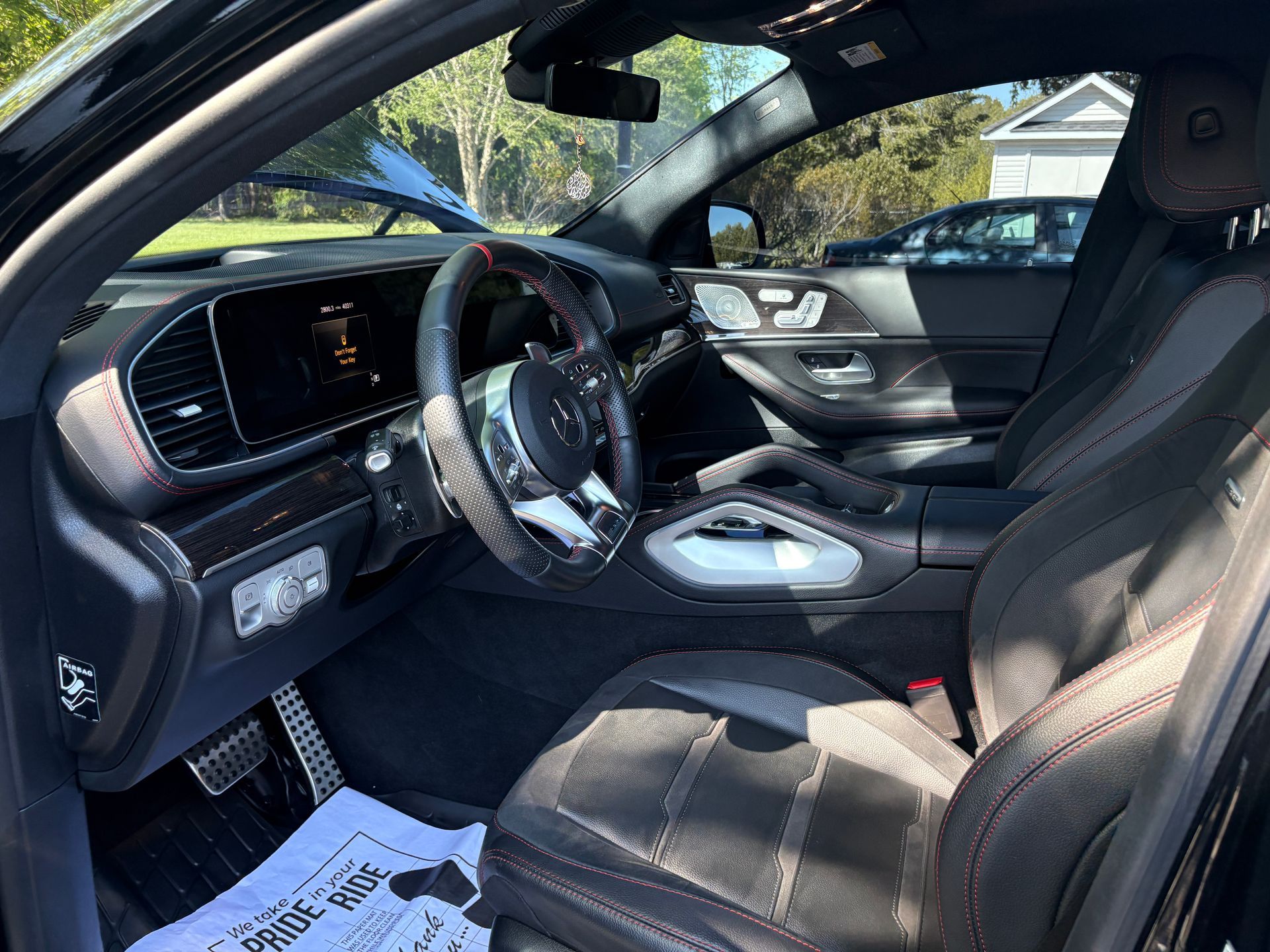 Interior of a black car with the driver’s door open, showing the front seats and dashboard in daylight