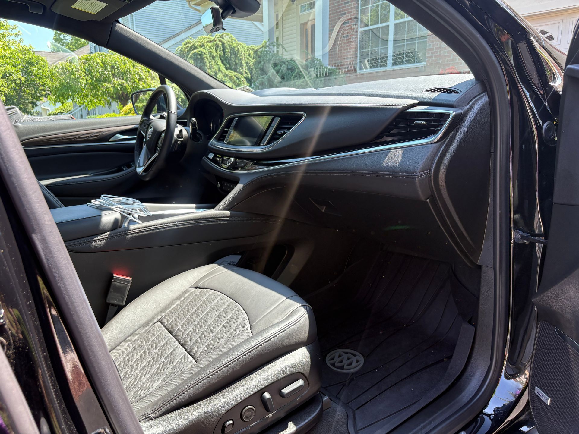 Driver’s seat and dashboard inside a black car with the door open in daylight