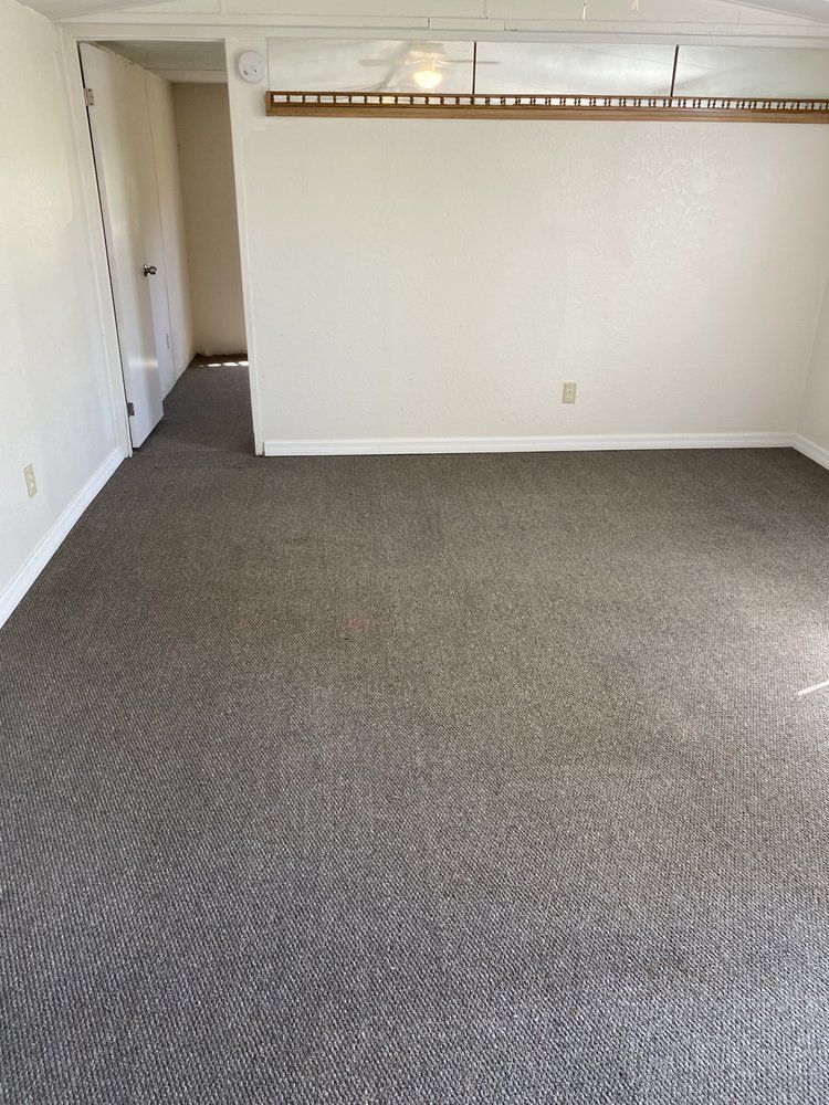 An empty living room with a gray carpet and white walls.