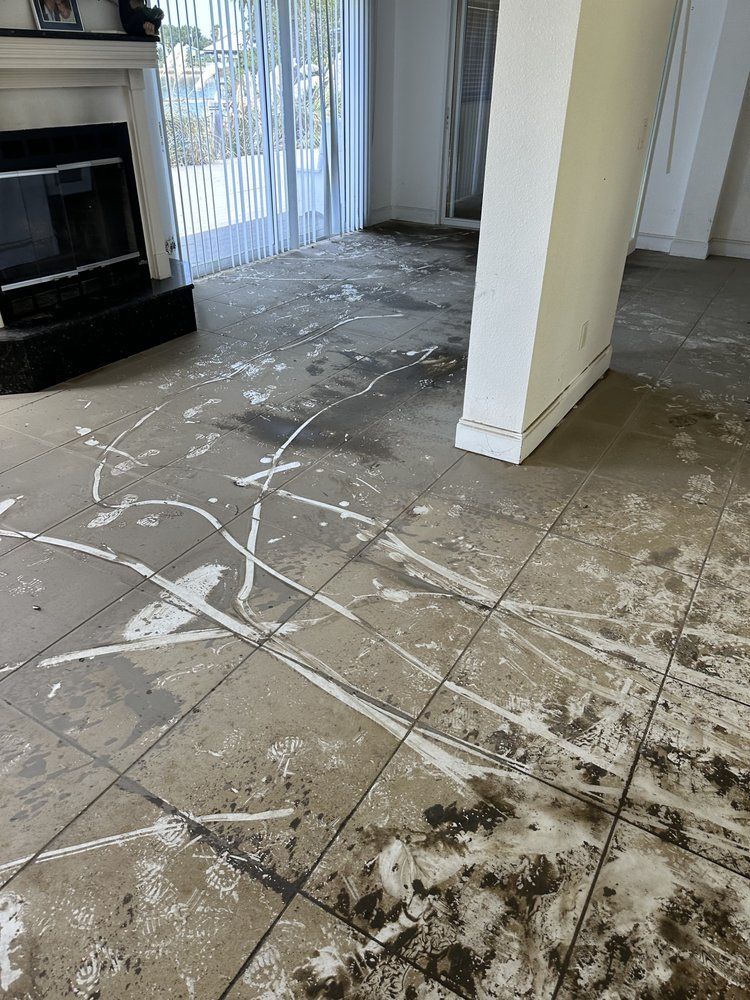 A living room with a dirty tile floor and a fireplace.