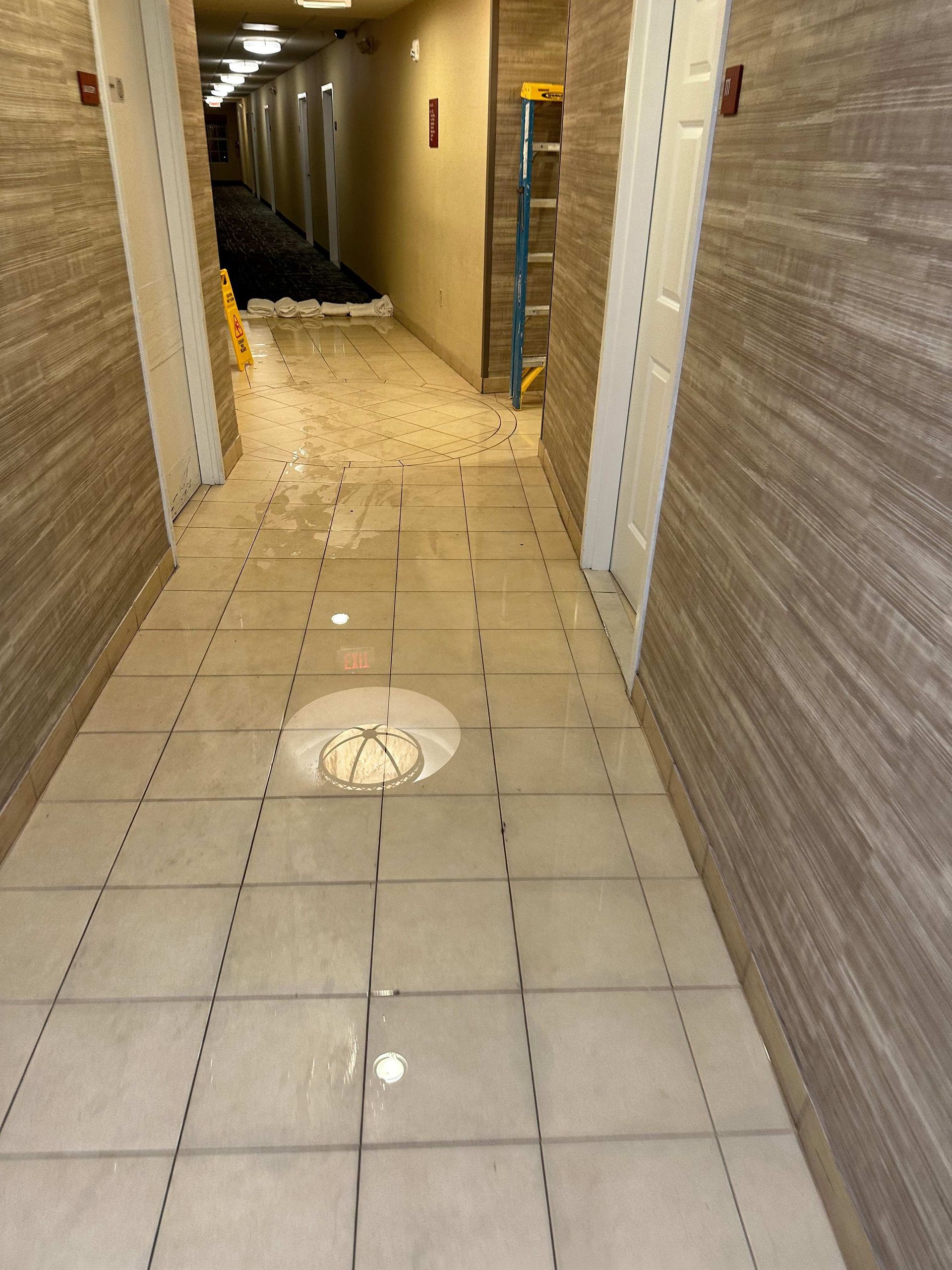 A hallway with a ladder and a puddle of water on the floor
