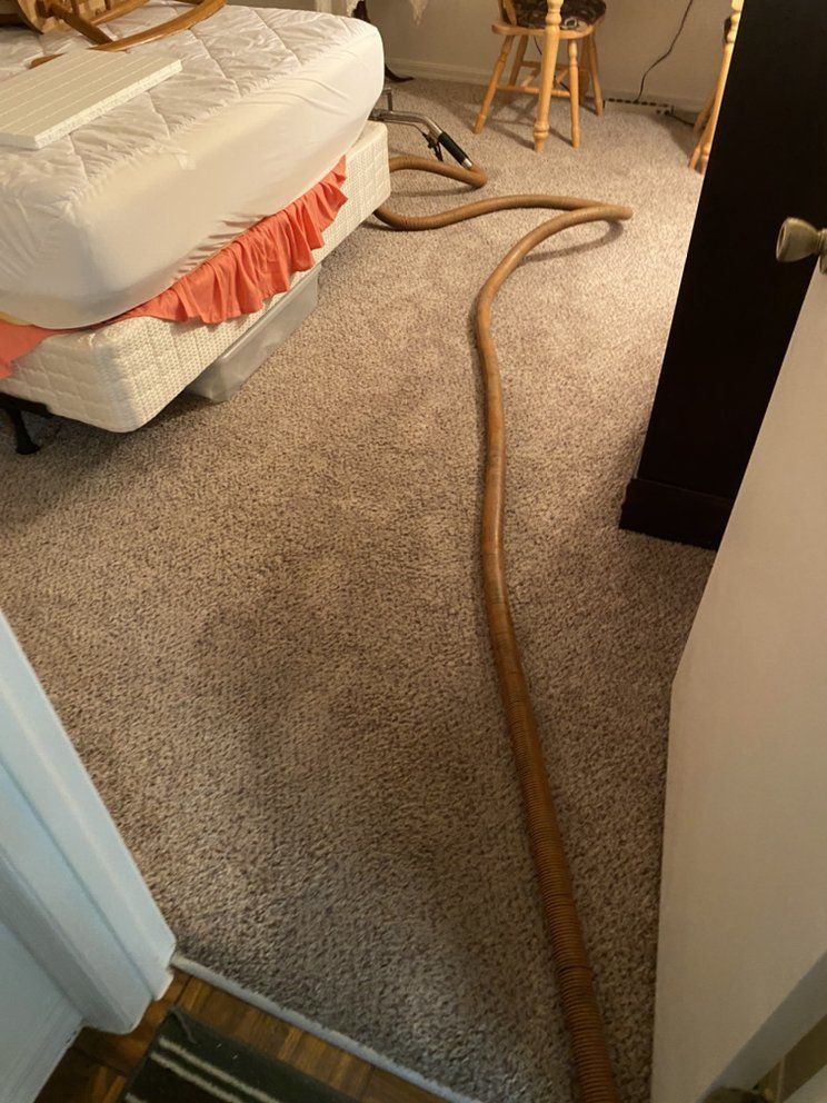 A bedroom with a mattress and a vacuum hose on the floor