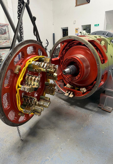 Primer plano del estator y el rotor de un motor eléctrico que se miden con un calibrador en un banco de trabajo.