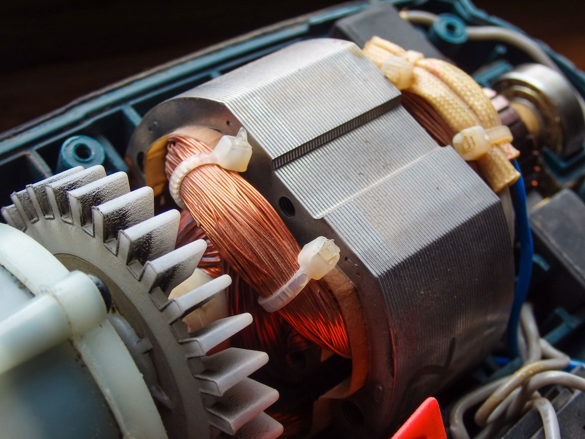 Primer plano del rotor de un motor eléctrico con bobinados de cobre y engranajes de plástico blanco.