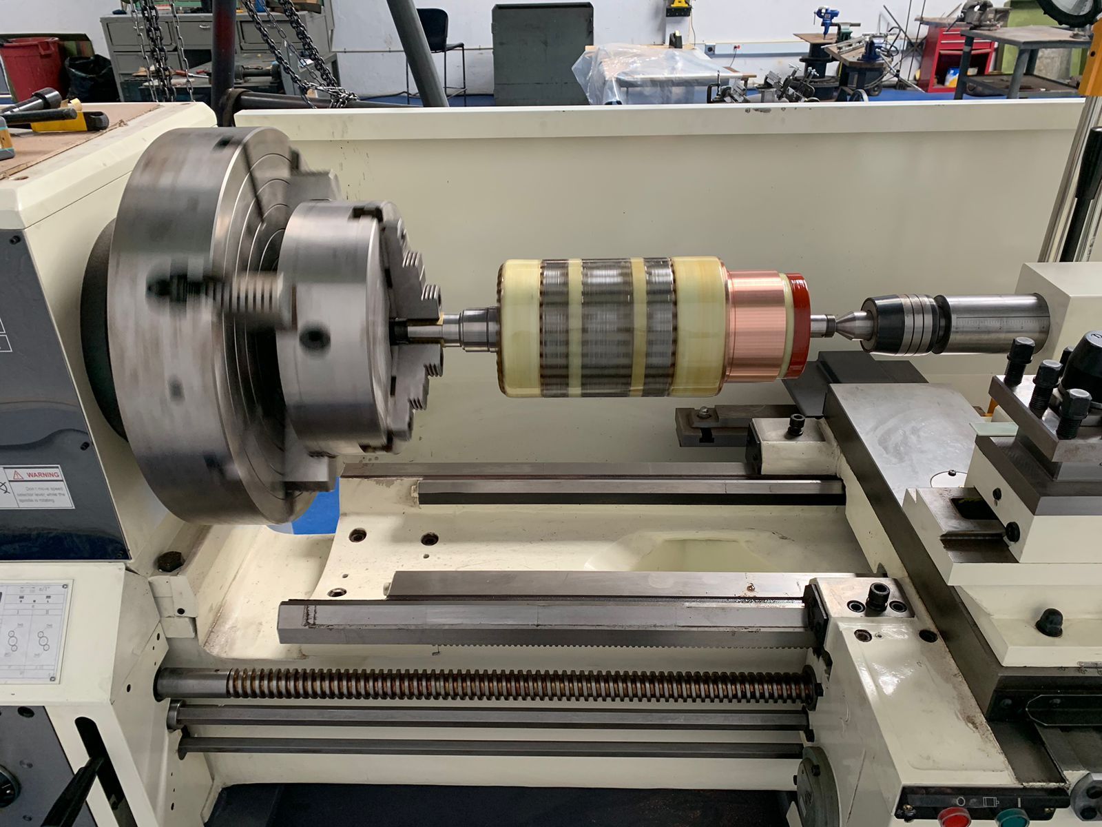 Torno con un rotor cilíndrico montado entre el mandril y el contrapunto en un taller.