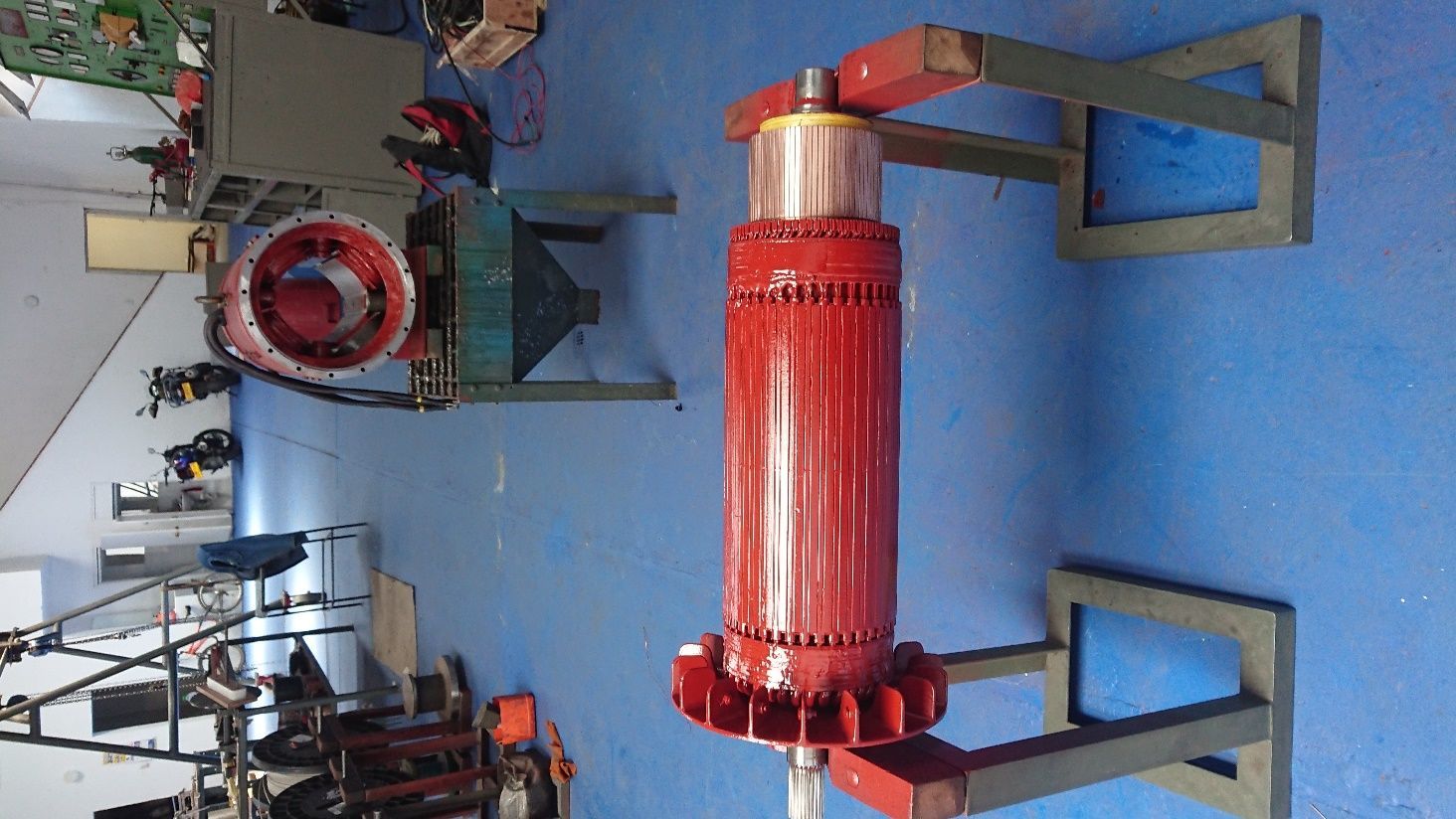 Taller con una gran máquina cilíndrica roja o bobina sobre un suelo azul