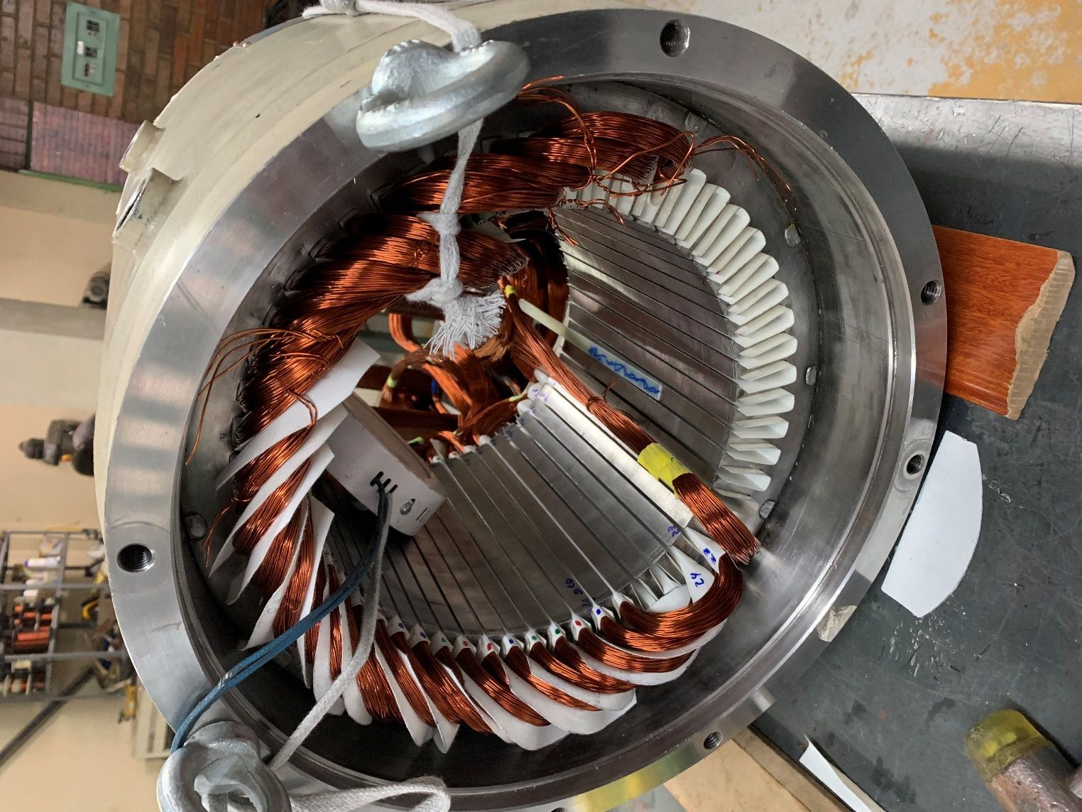 Primer plano del estator de un motor eléctrico metálico con bobinados de cobre dentro de un taller.