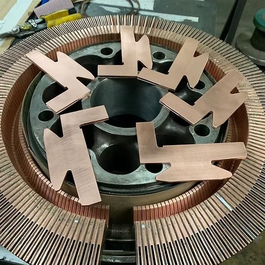 Estator de motor de cobre con varias pestañas metálicas dispuestas alrededor de la abertura central.
