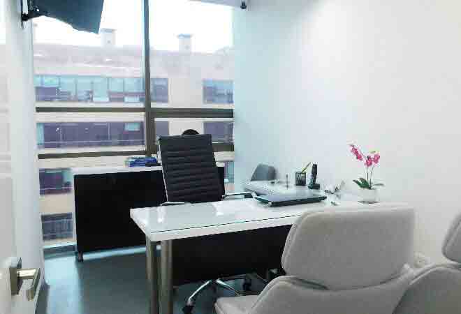 Dental office interior with white desk, black chair, window, and medical equipment.