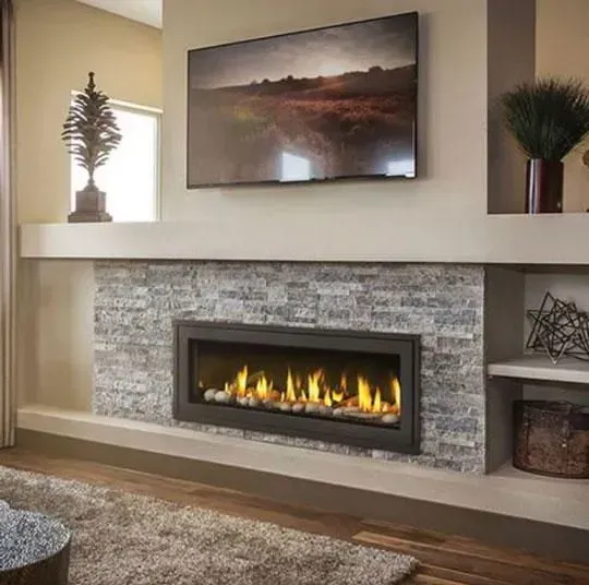 Fireplace with stone surround, lit flames, TV above, and decorative elements on a shelf.
