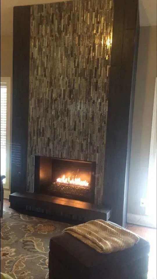 Modern fireplace with textured stone surround, flames, and a dark stone hearth.