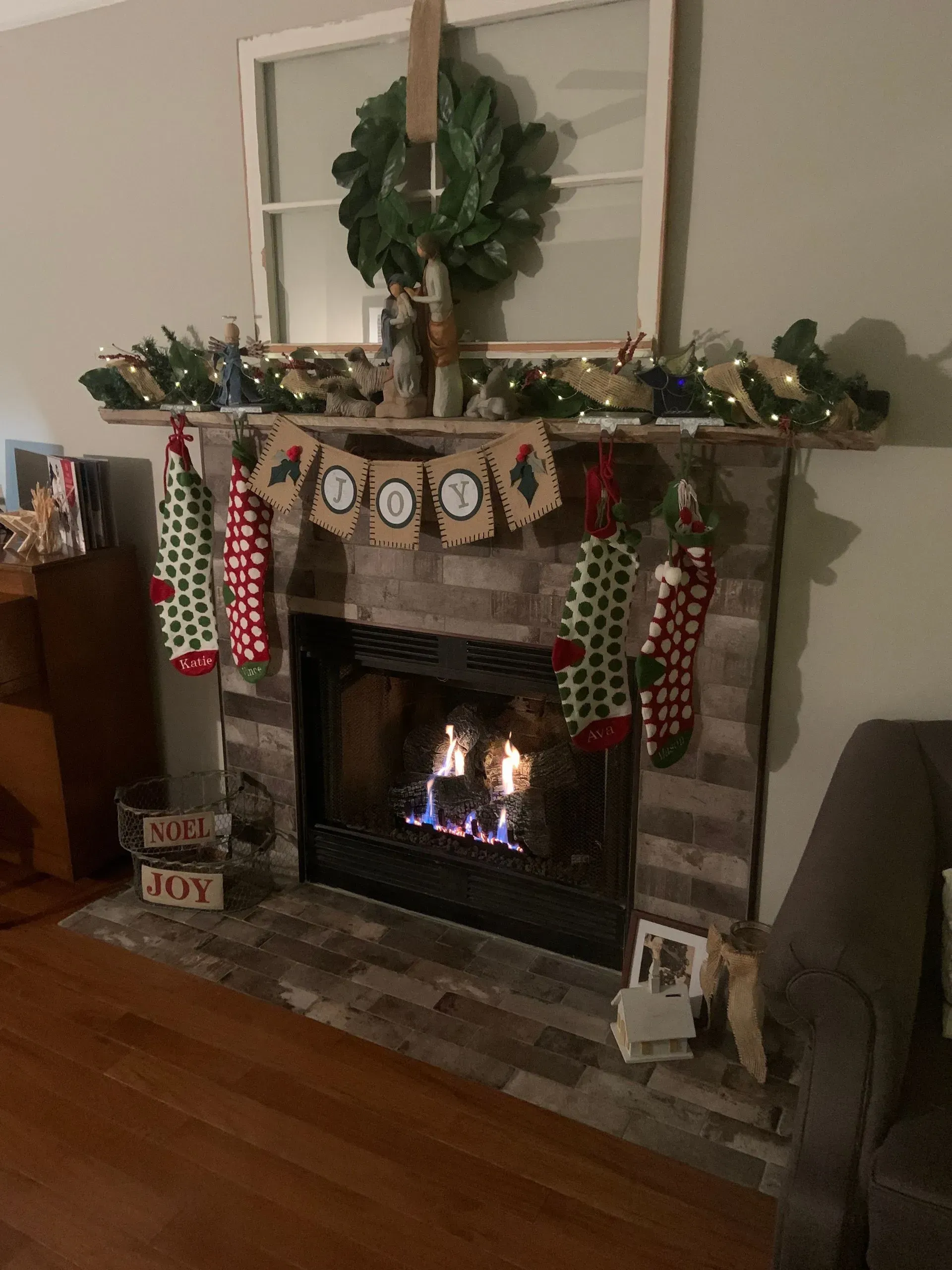 Fireplace with stacked stone facade, framed by white molding, topped with a mirror and dark wooden panel.
