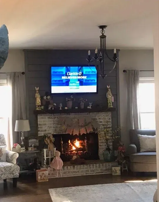 Living room with a lit fireplace, TV above, and Easter decorations.