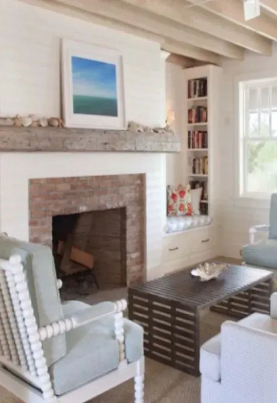 Cozy living room with fireplace, built-in bookshelf, and light blue armchairs, decorated in neutral colors.