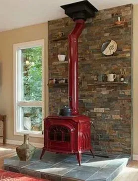 Red cast iron stove against a brick wall with shelves; a window to the left.