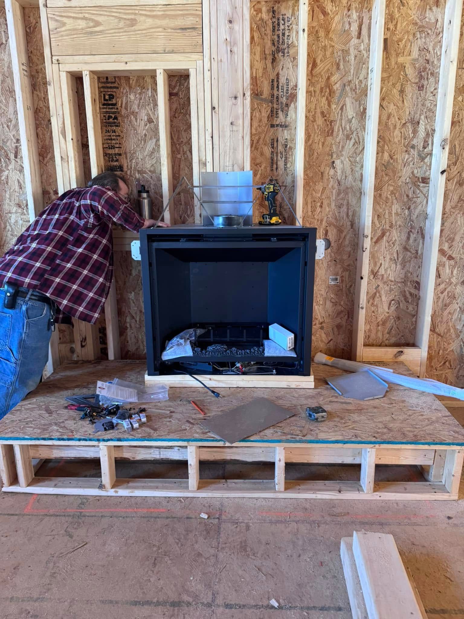 Person installing a fireplace in a wood-framed structure.