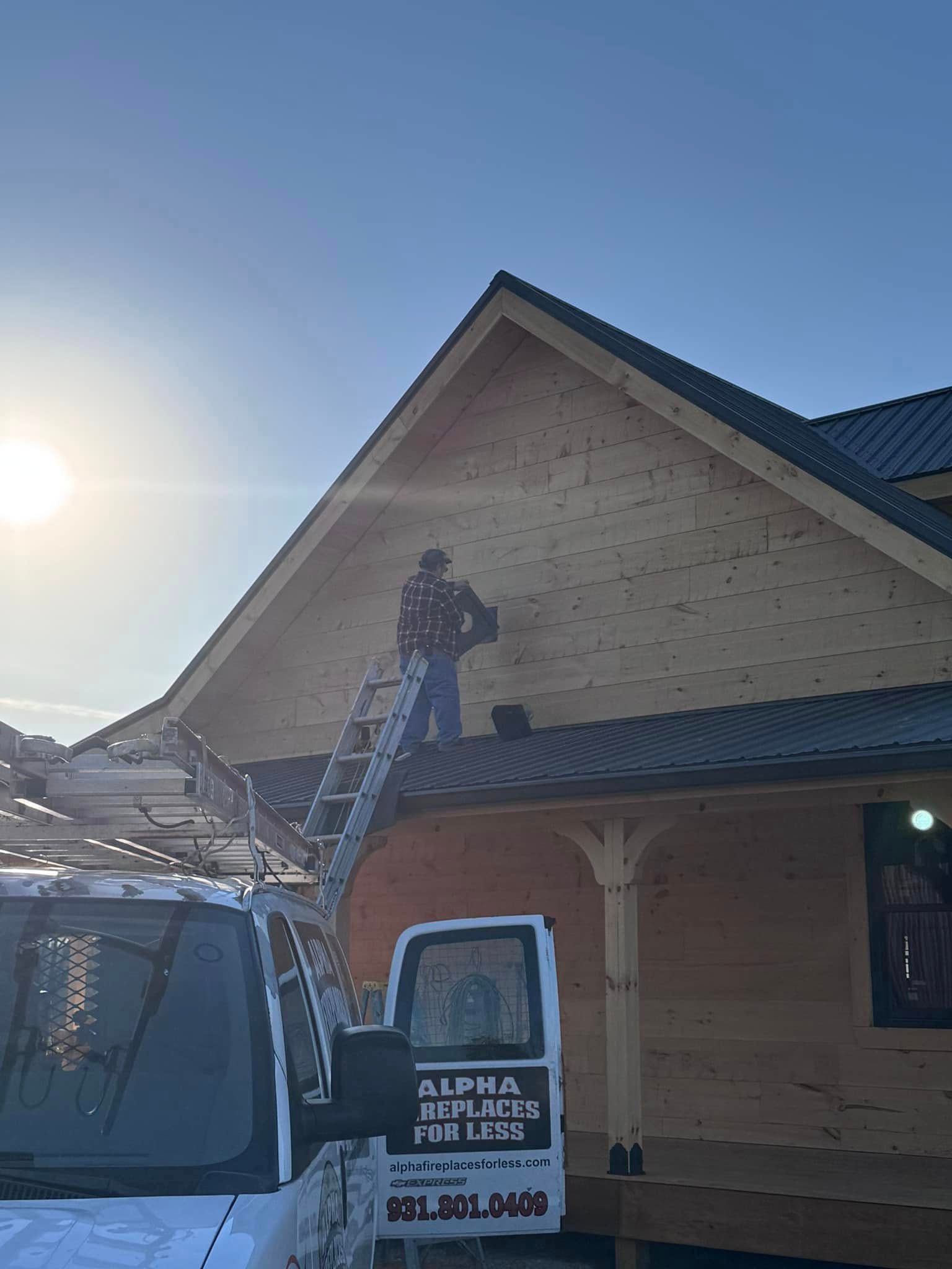 Person on a ladder working on a roof; a truck with business name is in the foreground. Bright sunny day.