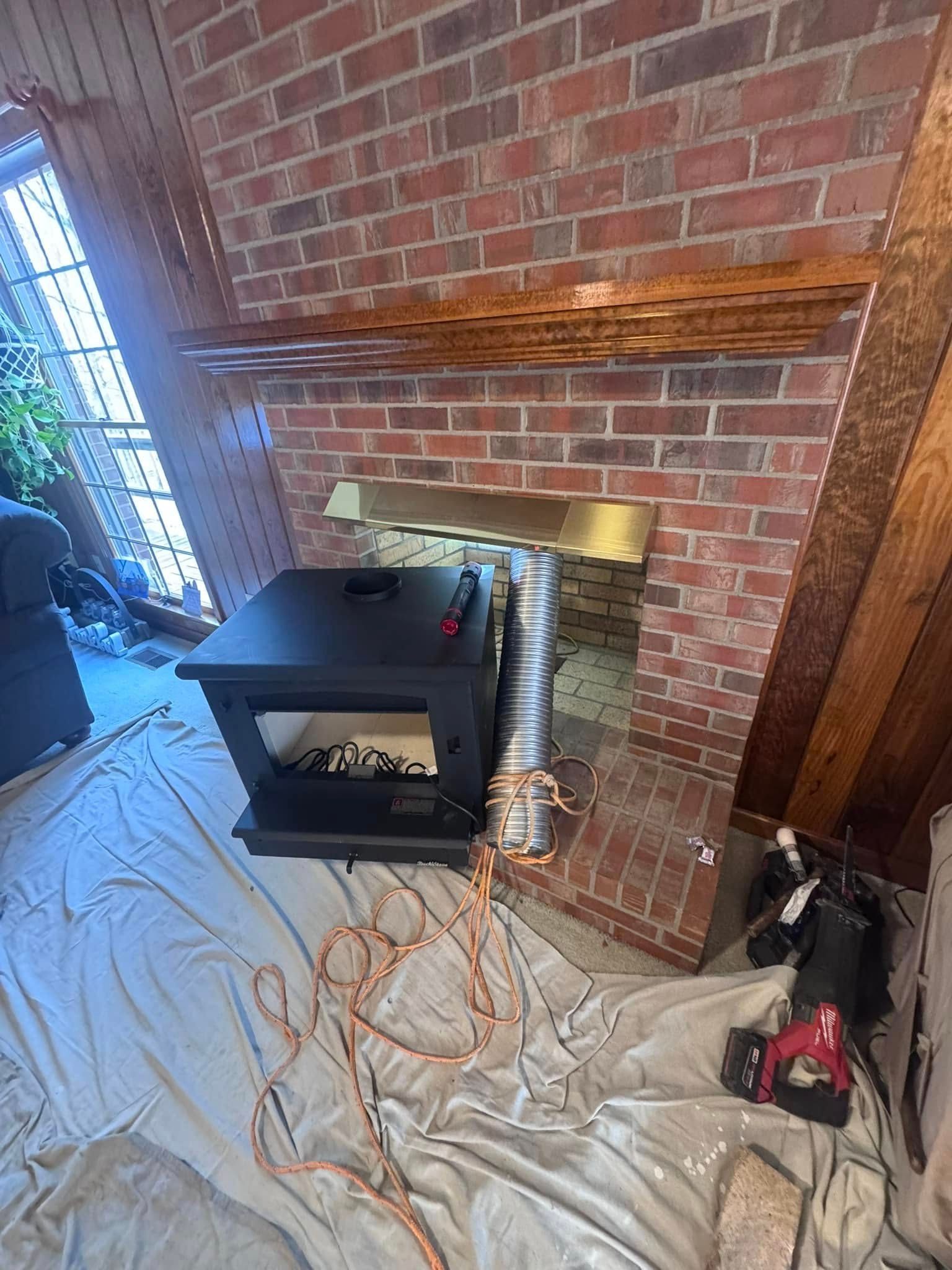 A wood stove sits in front of a brick fireplace, connected to the chimney by silver pipe.