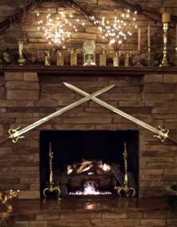 Two crossed swords above a fireplace with festive lights and decorations.