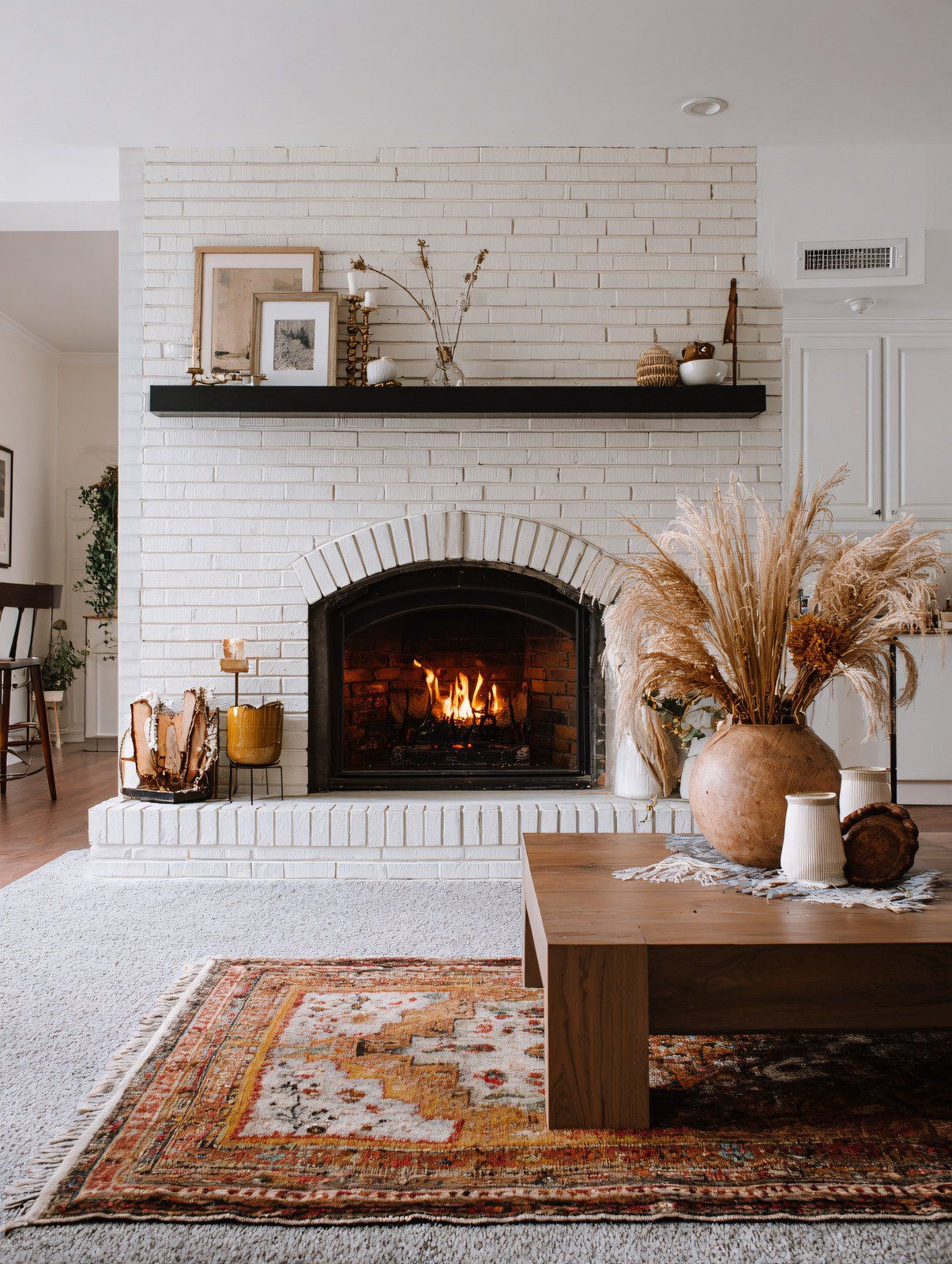 Fireplace with lit fire surrounded by mosaic tile, topped with decorations and a mirror.