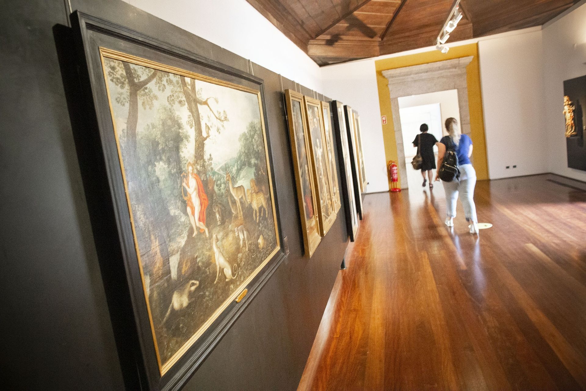 Um grupo de pessoas está olhando pinturas em um museu.