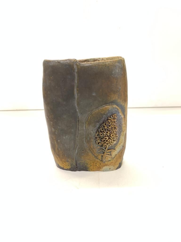 Um pequeno vaso de cerâmica está sobre uma superfície branca.