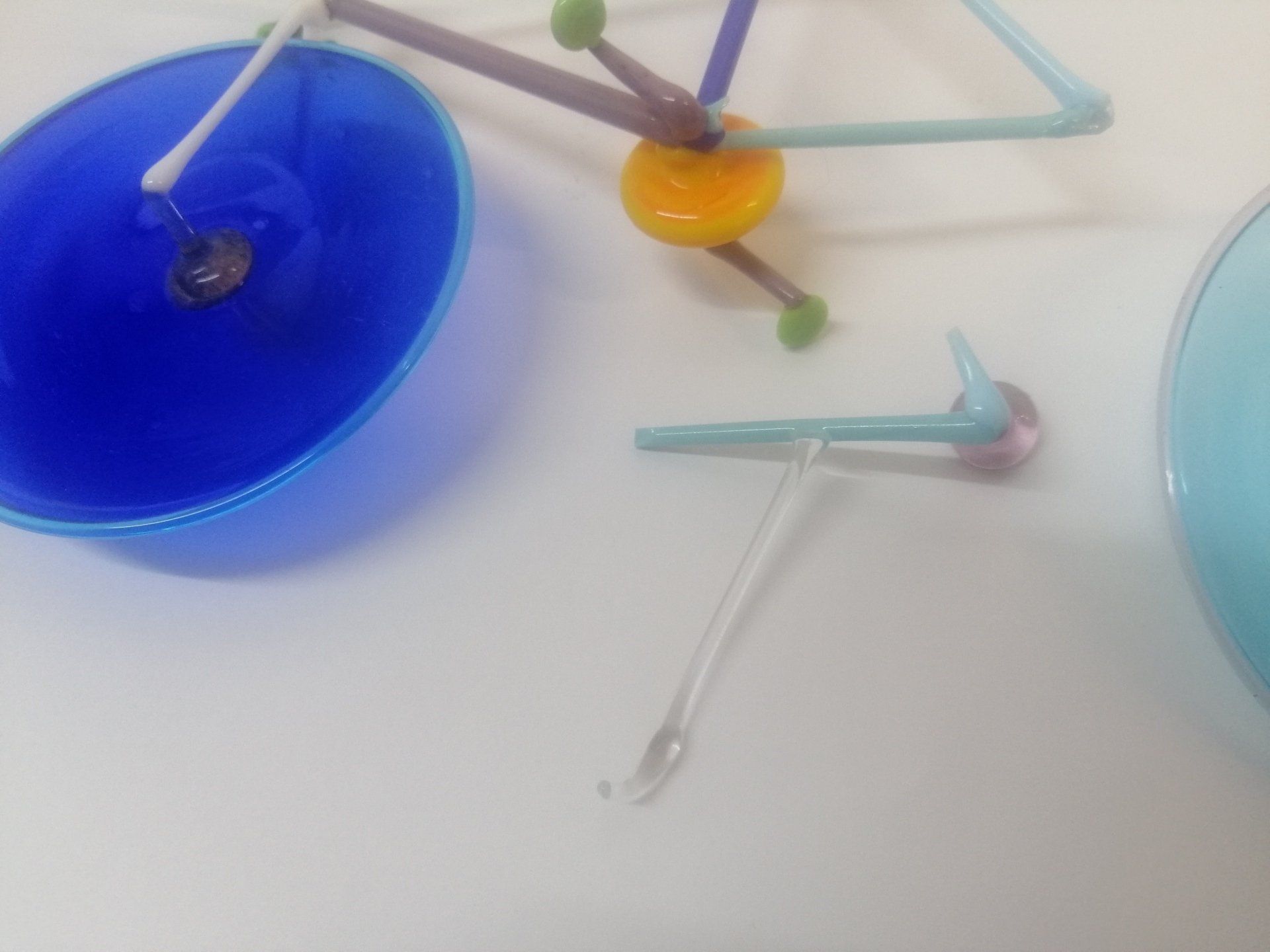 Uma tigela azul fica sobre uma mesa ao lado de um objeto colorido