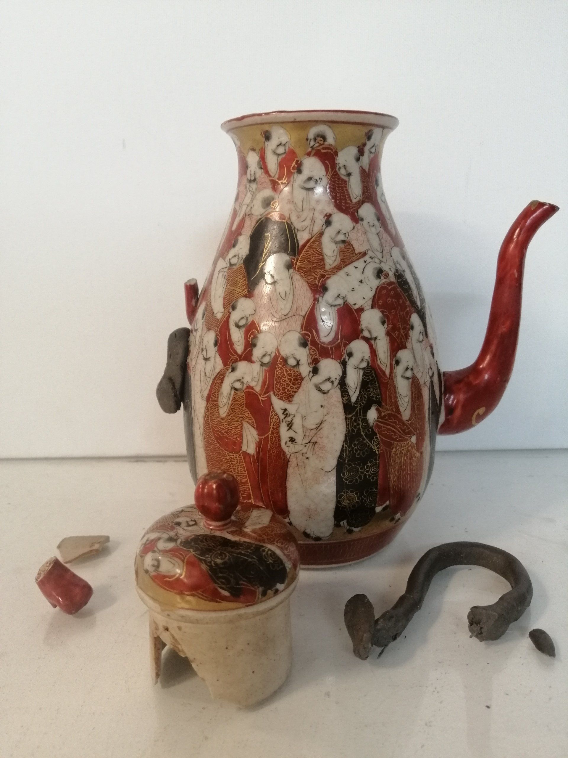 Um vaso quebrado com uma alça vermelha e uma tampa