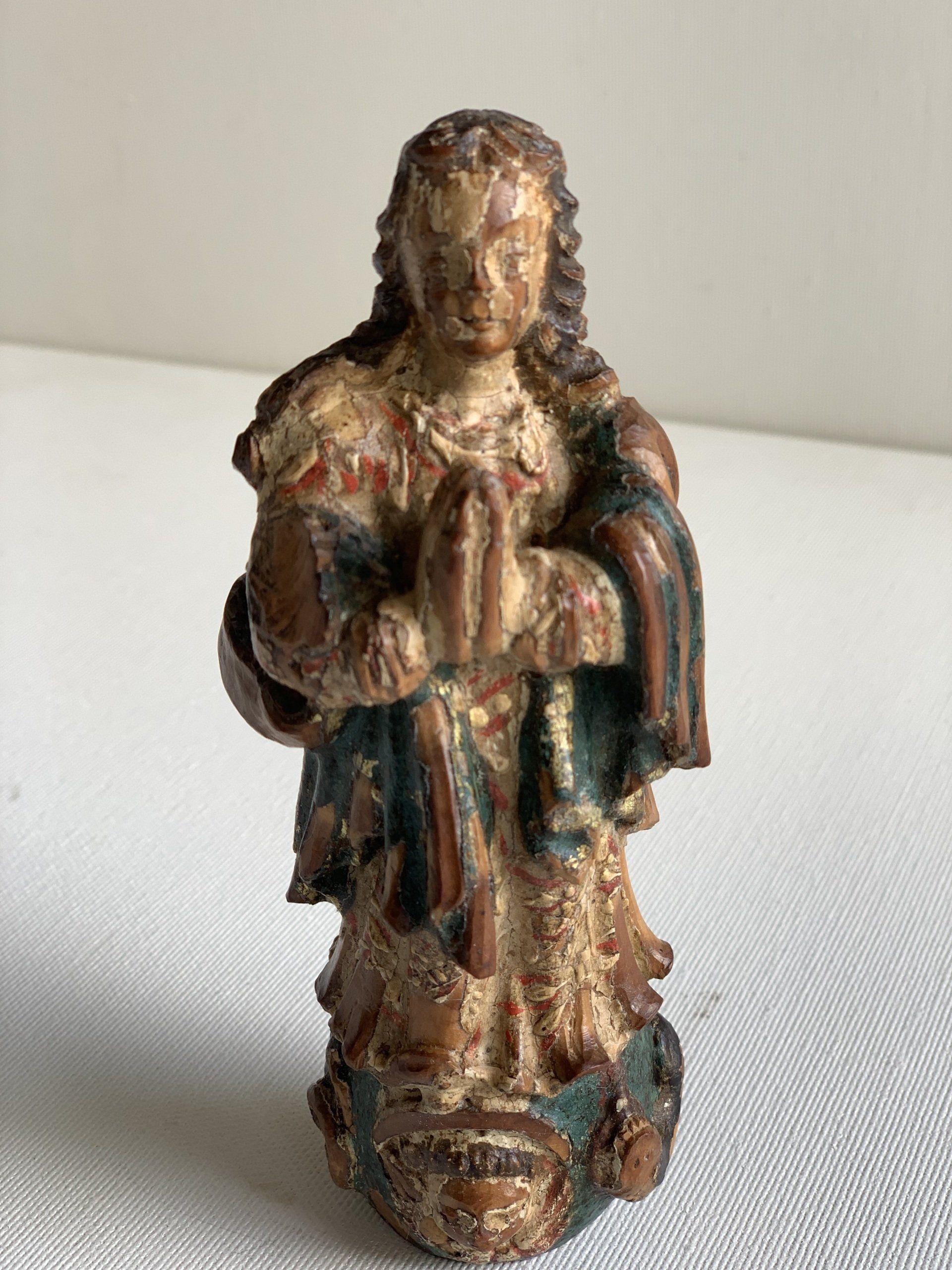 Uma estátua de uma mulher com as mãos cruzadas está sentada sobre uma mesa.