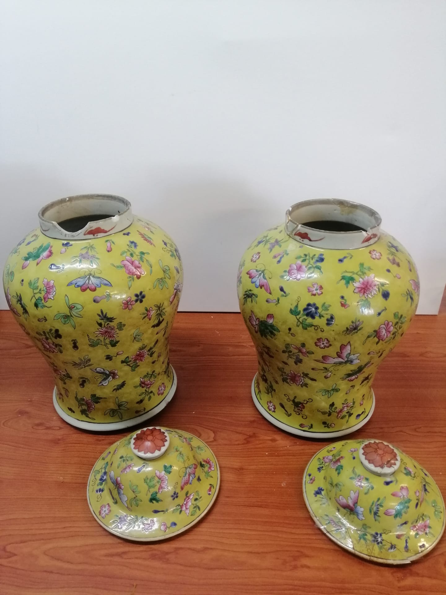 Um par de vasos amarelos com flores estão sobre uma mesa de madeira.