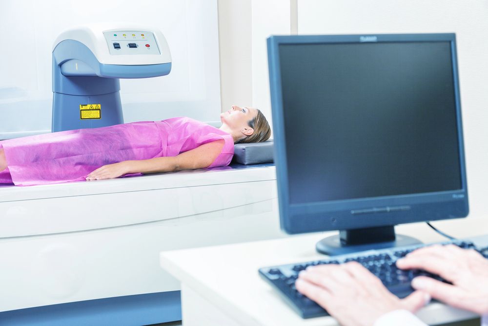 Una mujer está acostada en una cama frente a una computadora.