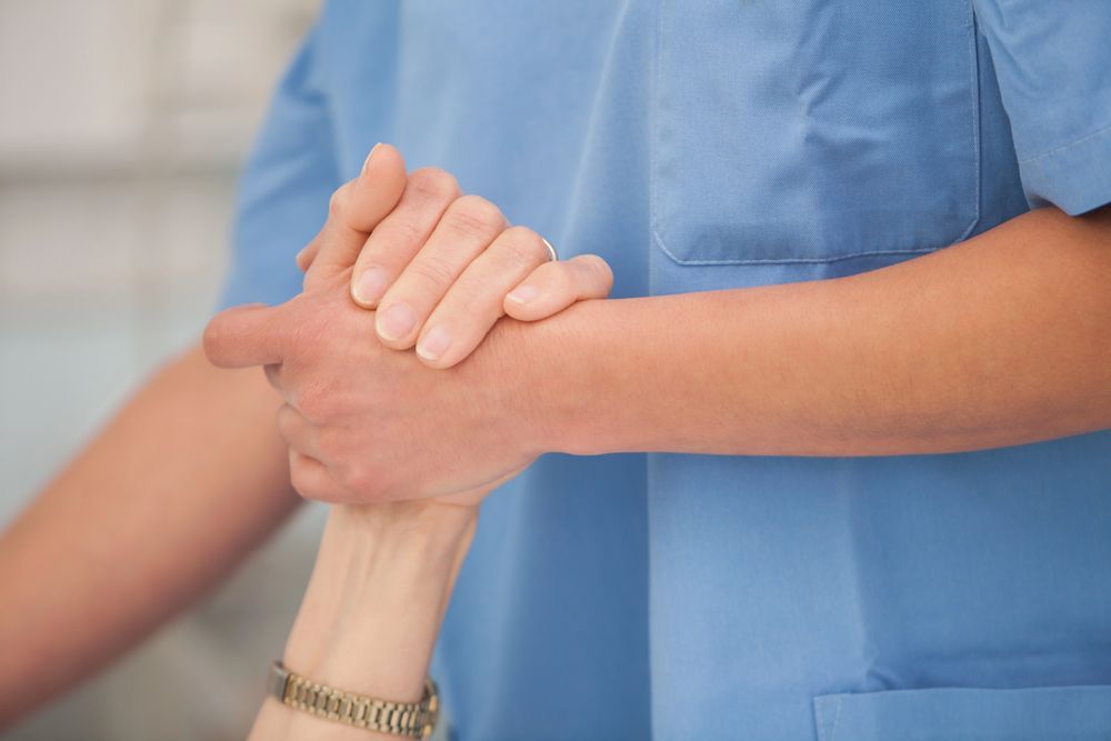 Una enfermera sostiene la mano de un paciente en un hospital.