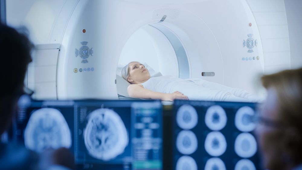 Una mujer está acostada en una cama de hospital y le están haciendo una tomografía computarizada.