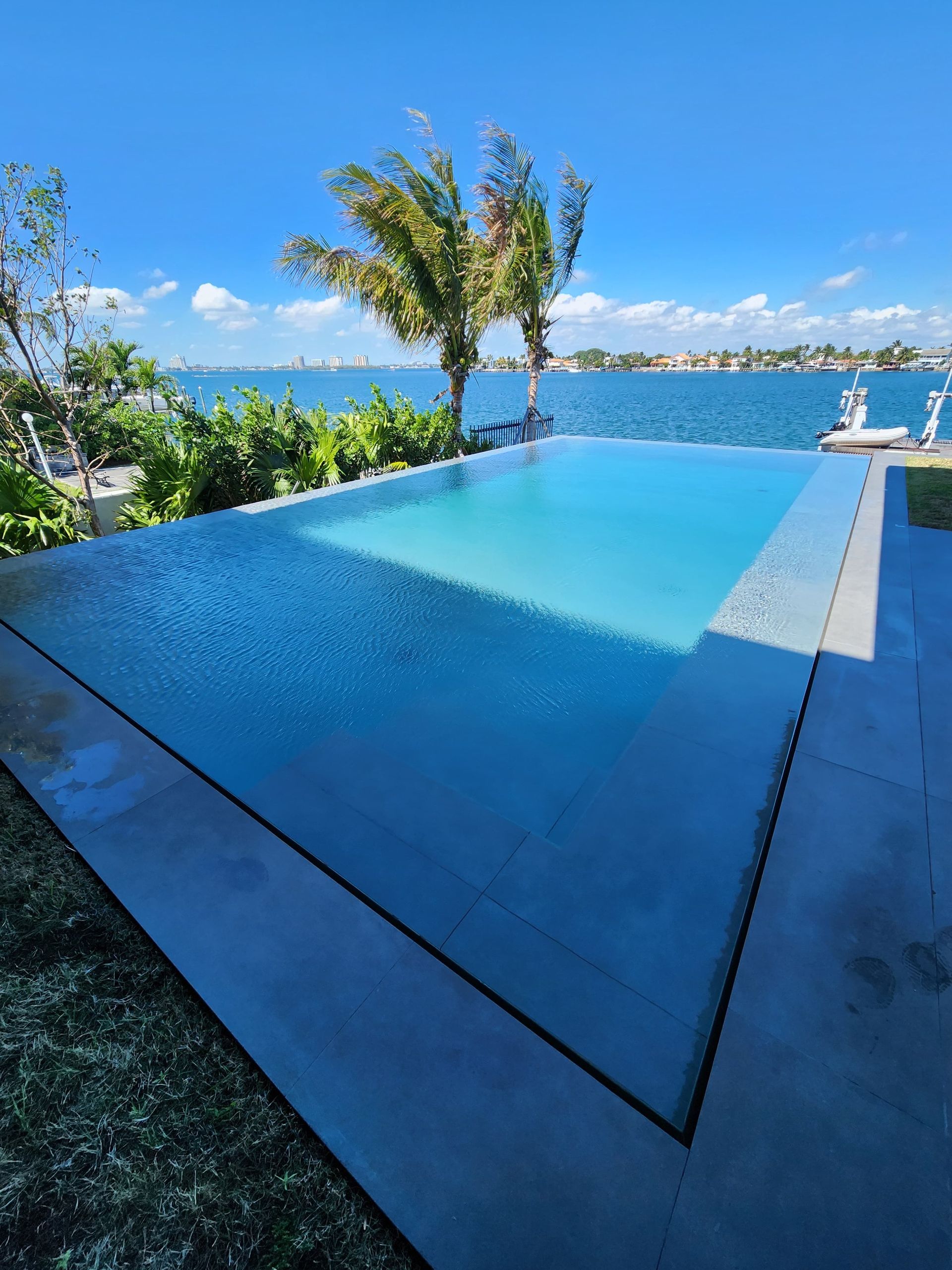 An infinity pool overlooks a body of water under a blue sky.