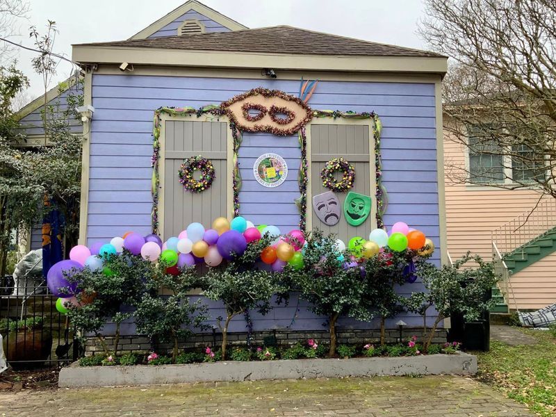 Lilac house decorated for Mardi Gras with balloons, masks, and wreaths.