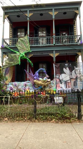 Two-story house decorated for Mardi Gras with dragon and figures, beads, purple, green, gold, and red.
