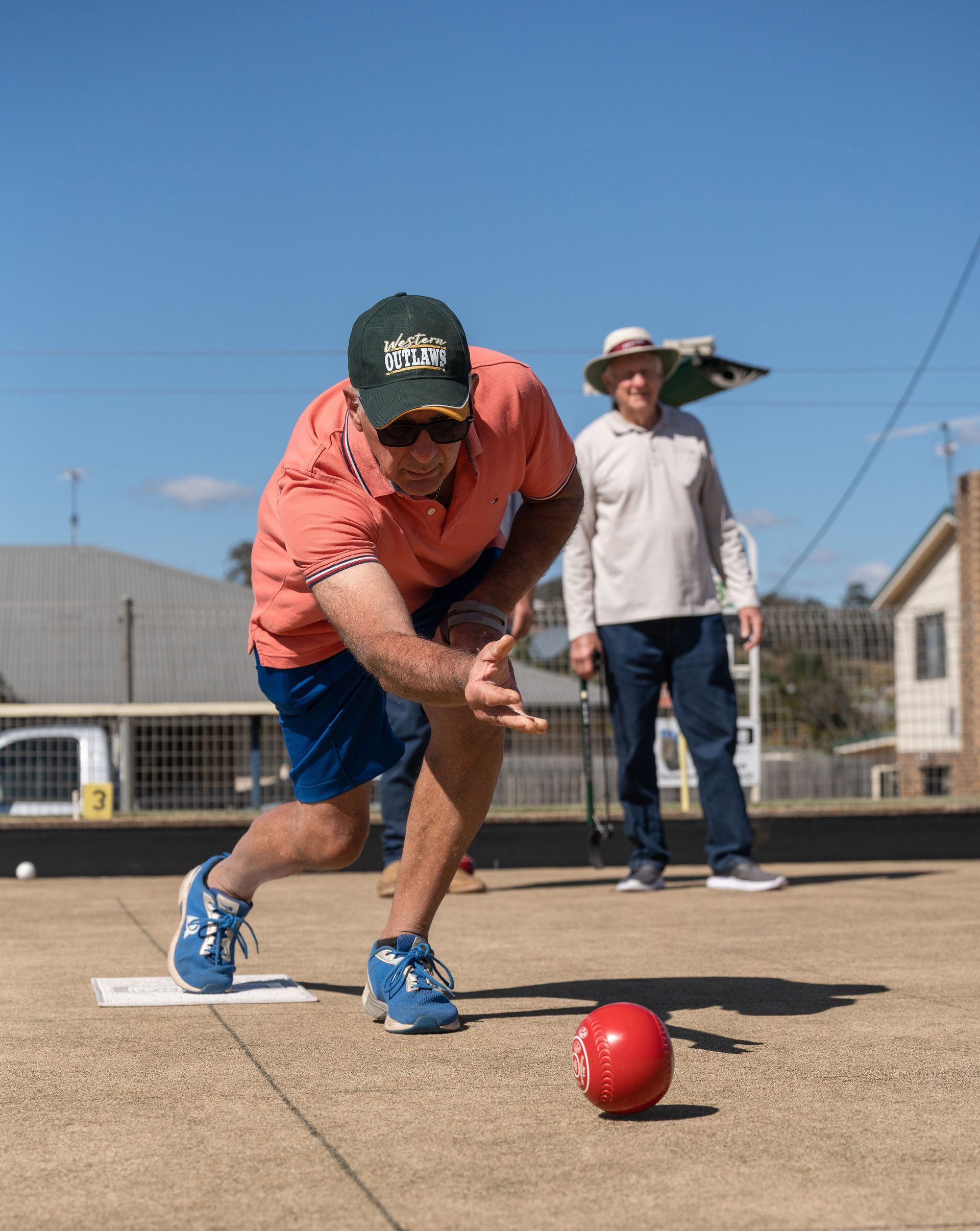 Golfer putting an orange ball on green turf with a putter